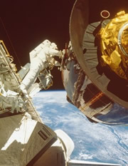 Astronaut walking in space between shuttle and space station