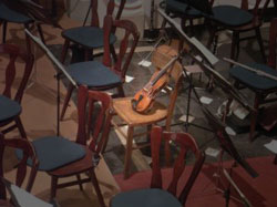 Violin surrounded by empty chairs