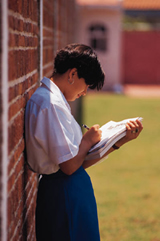 Girl leaning against wall studying book
