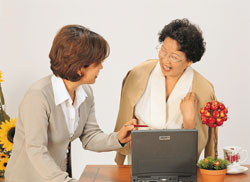 Woman and her mother laughing while at computer