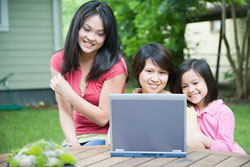 Mother and two daughters at computer