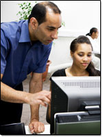 Teacher helping student working on a computer.