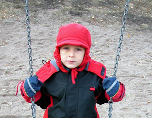 Boy with red hat sitting on the swing