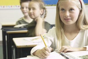 Student, seated and looking at teacher from her desk