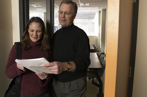 Male and female teachers standing in a hallway reviewing work