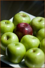 green apples surrounding one red apple