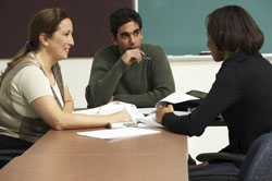 Three people talking in a classroom